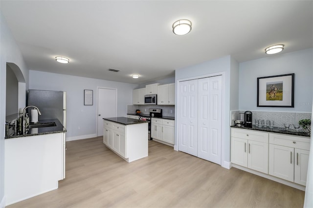 kitchen with sink, white cabinets, light wood-type flooring, and appliances with stainless steel finishes