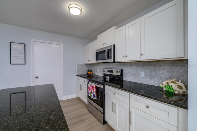 kitchen featuring stainless steel appliances, white cabinetry, and dark stone counters