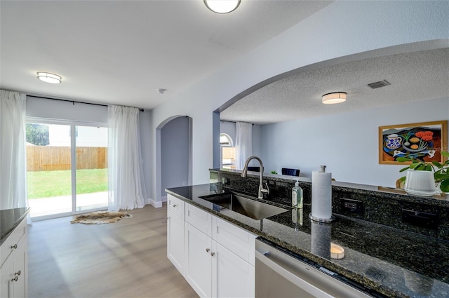 kitchen featuring dark stone countertops, sink, white cabinets, and light wood-type flooring