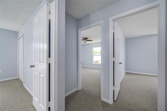 hall with a textured ceiling and light carpet