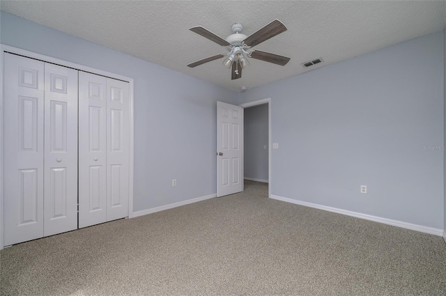 unfurnished bedroom with carpet flooring, ceiling fan, a closet, and a textured ceiling