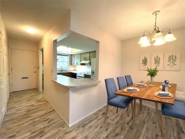 dining area with wood-type flooring, a notable chandelier, and sink