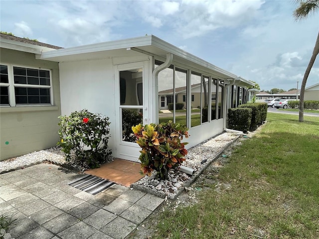 view of side of home featuring a sunroom and a yard