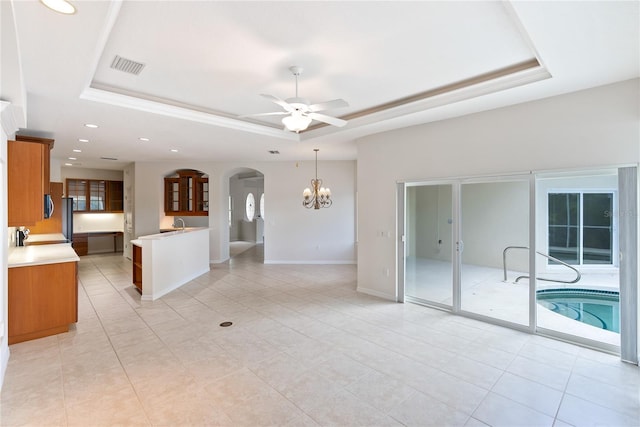 interior space with ceiling fan with notable chandelier, a tray ceiling, and a wealth of natural light