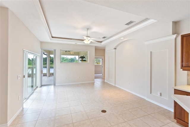 unfurnished room with light tile patterned floors, a raised ceiling, ceiling fan, and ornamental molding