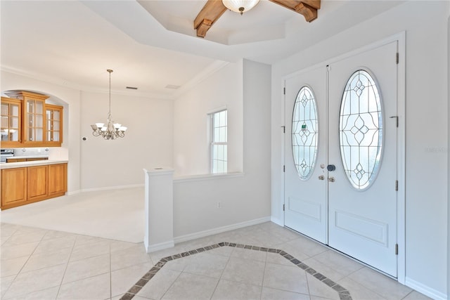 tiled entrance foyer featuring a tray ceiling, crown molding, and a notable chandelier