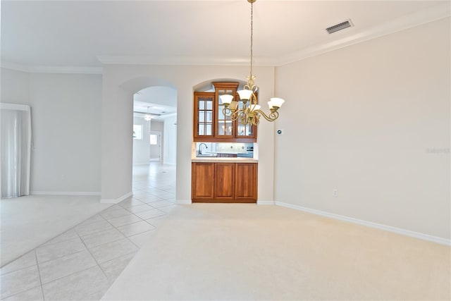 unfurnished dining area featuring sink, ceiling fan with notable chandelier, light colored carpet, and crown molding