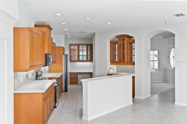 kitchen with backsplash, light tile patterned flooring, and stainless steel appliances