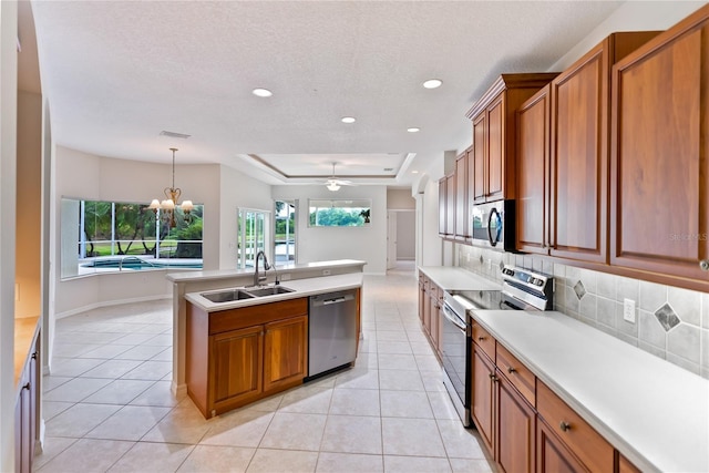 kitchen with sink, stainless steel appliances, a raised ceiling, pendant lighting, and ceiling fan with notable chandelier