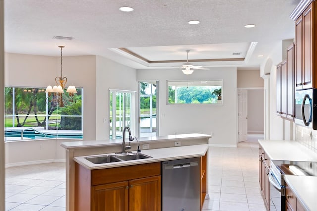 kitchen with ceiling fan with notable chandelier, sink, stainless steel appliances, and a tray ceiling