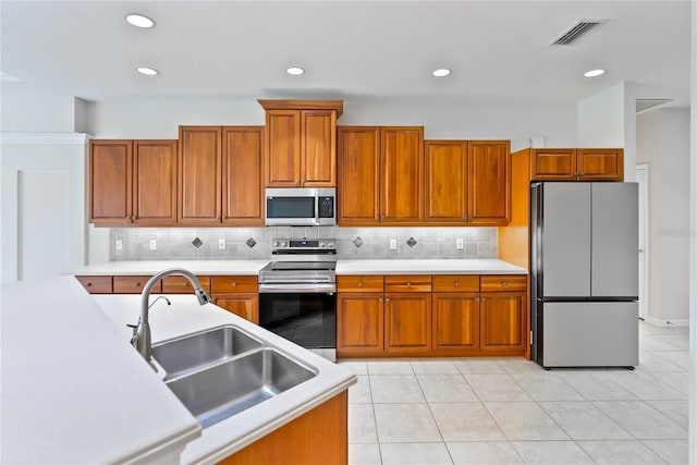 kitchen with appliances with stainless steel finishes, backsplash, light tile patterned floors, and sink