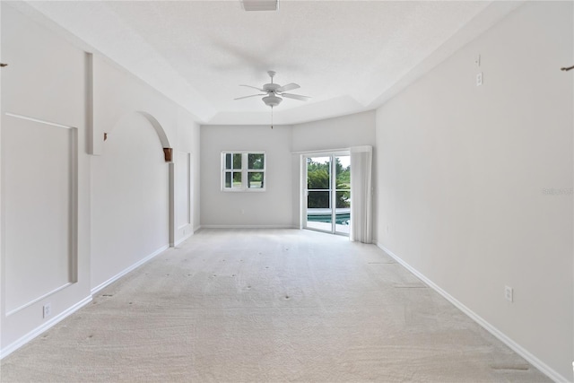 carpeted empty room featuring ceiling fan and a raised ceiling