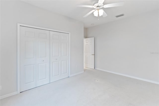 unfurnished bedroom featuring ceiling fan, light colored carpet, and a closet