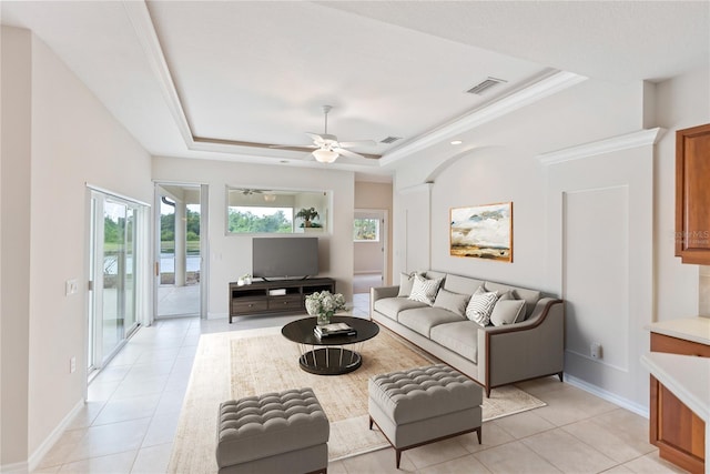 living room featuring light tile patterned floors, a tray ceiling, and ceiling fan