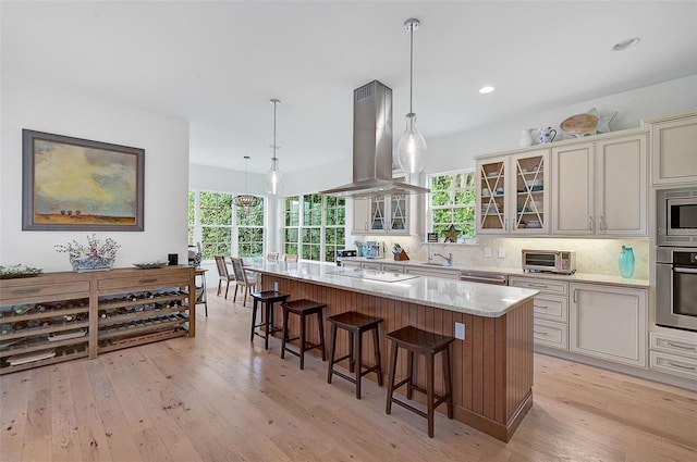 kitchen featuring hanging light fixtures, island range hood, a breakfast bar, a kitchen island, and appliances with stainless steel finishes