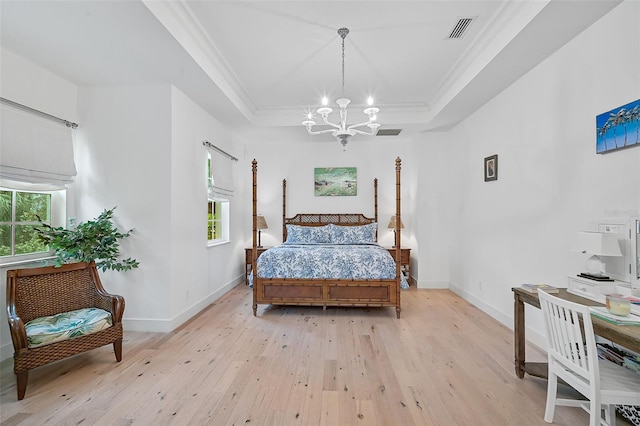 bedroom with a notable chandelier, light hardwood / wood-style floors, a raised ceiling, and ornamental molding