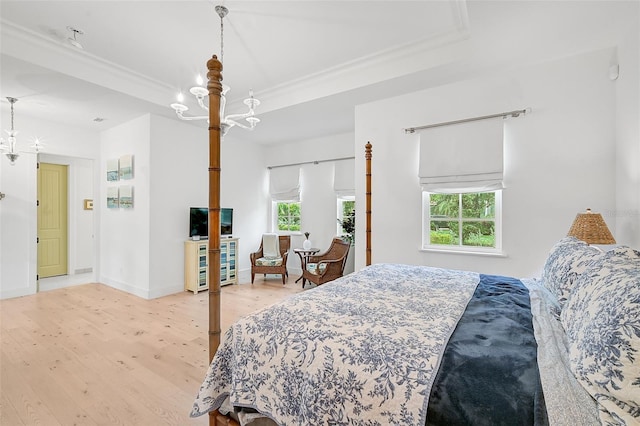 bedroom featuring light hardwood / wood-style flooring, ornamental molding, and a notable chandelier