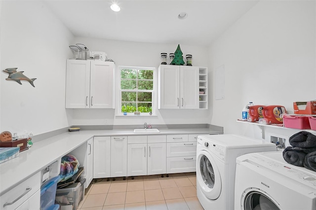 clothes washing area featuring washing machine and clothes dryer, sink, light tile patterned floors, and cabinets