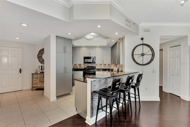 kitchen featuring gray cabinetry, black appliances, a kitchen breakfast bar, crown molding, and kitchen peninsula