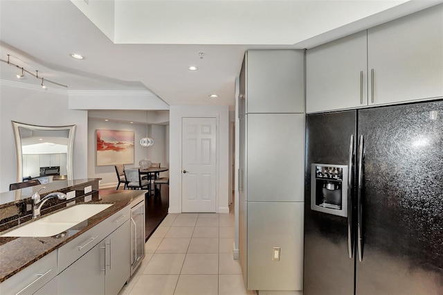 kitchen with black fridge, sink, dark stone countertops, light tile patterned floors, and ornamental molding