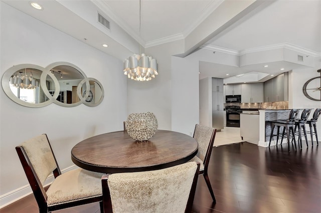 dining space featuring dark hardwood / wood-style flooring, crown molding, and a chandelier