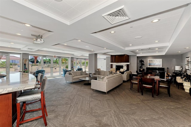 interior space with coffered ceiling, a healthy amount of sunlight, a tray ceiling, and french doors