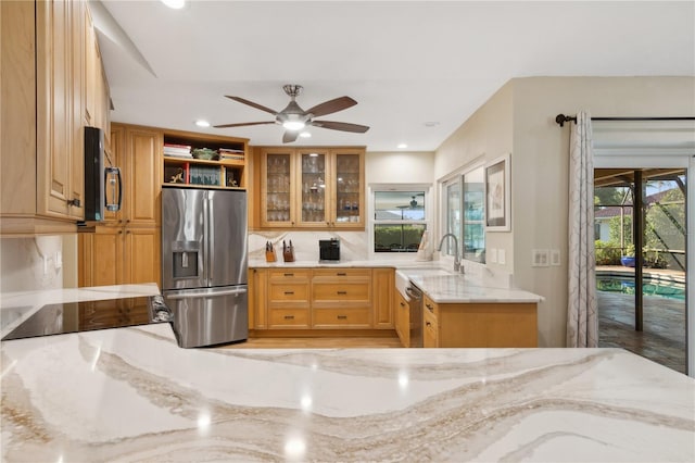 kitchen featuring sink, ceiling fan, light stone countertops, tasteful backsplash, and stainless steel appliances