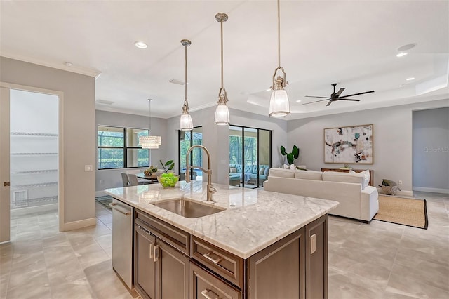 kitchen featuring light stone counters, plenty of natural light, sink, a center island with sink, and hanging light fixtures