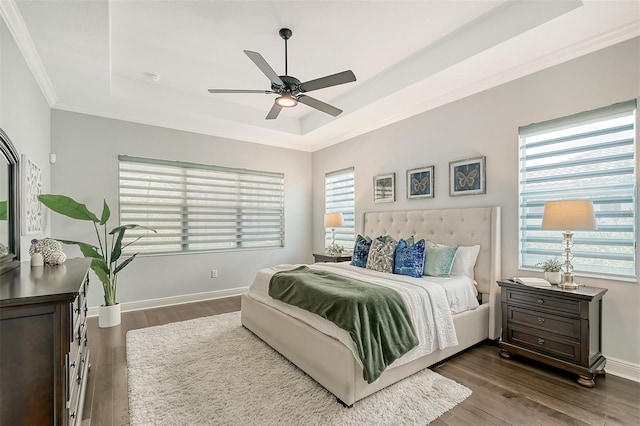 bedroom with dark hardwood / wood-style floors, a raised ceiling, multiple windows, and ceiling fan