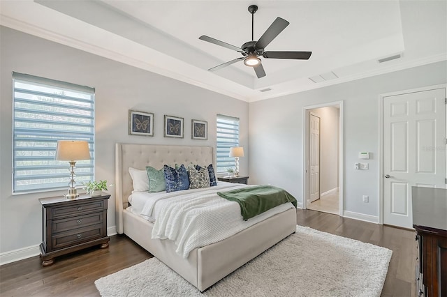 bedroom featuring dark hardwood / wood-style flooring, a tray ceiling, ceiling fan, and crown molding