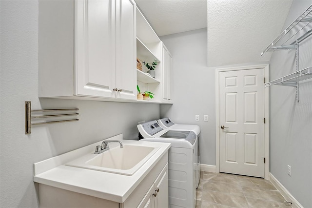 laundry area with cabinets, a textured ceiling, sink, light tile patterned floors, and washing machine and dryer