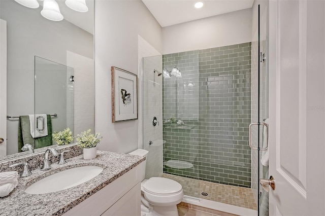 bathroom featuring tile patterned floors, vanity, toilet, and a shower with door