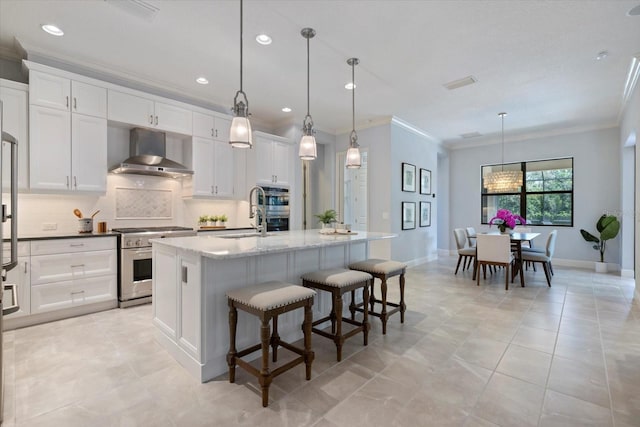 kitchen featuring tasteful backsplash, visible vents, appliances with stainless steel finishes, wall chimney range hood, and a sink