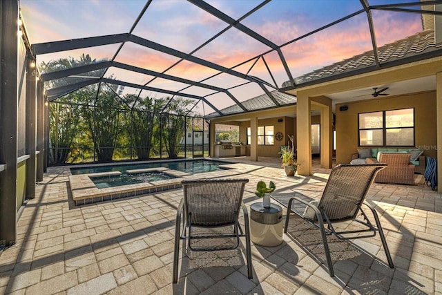 patio terrace at dusk with a pool with connected hot tub, ceiling fan, a lanai, and an outdoor hangout area