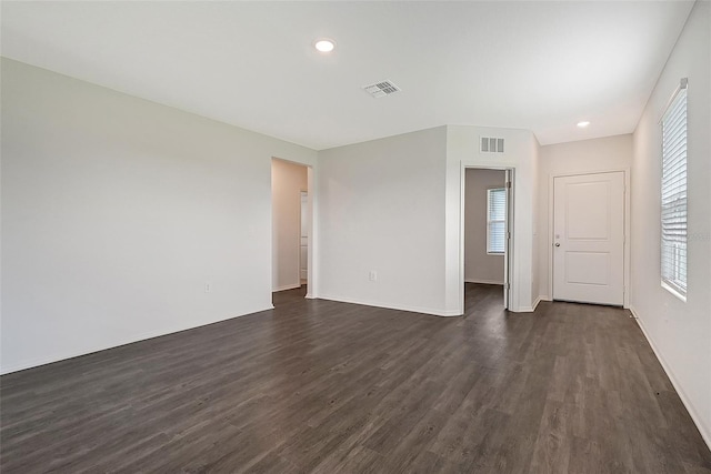 empty room with dark hardwood / wood-style flooring and plenty of natural light