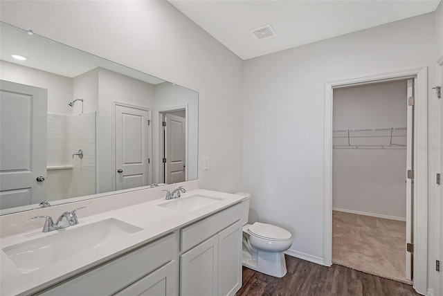 bathroom featuring hardwood / wood-style floors, vanity, toilet, and a shower