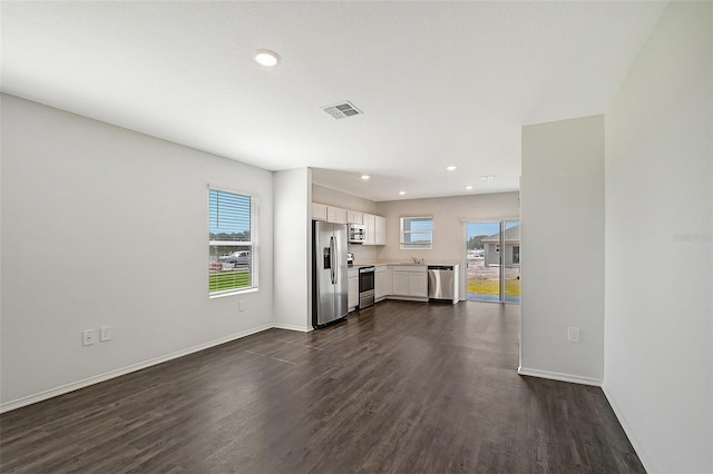 unfurnished living room featuring a wealth of natural light, sink, and dark hardwood / wood-style floors