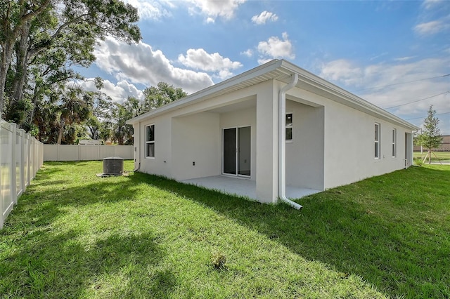 rear view of house featuring a lawn, a fenced backyard, a patio, and stucco siding
