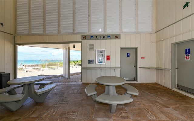 interior space featuring a water view, a towering ceiling, and a view of the beach