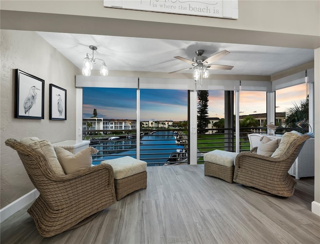 living room featuring ceiling fan with notable chandelier, wood-type flooring, and a water view