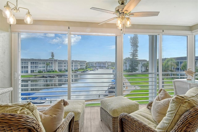 sunroom featuring ceiling fan and a water view