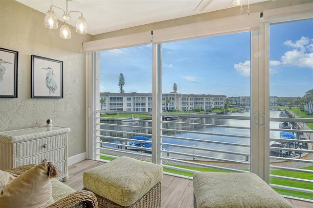 sunroom / solarium with a water view and a notable chandelier