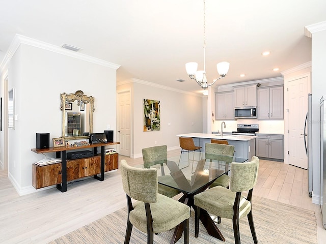 dining room featuring a chandelier, light wood-type flooring, and crown molding