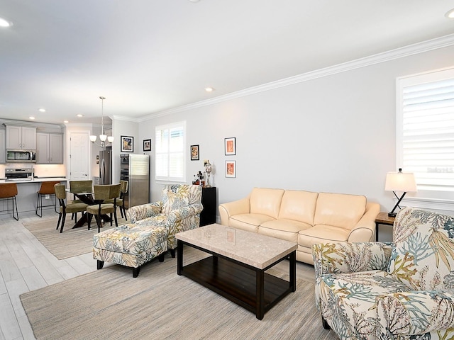 living room featuring light hardwood / wood-style floors, ornamental molding, and a notable chandelier