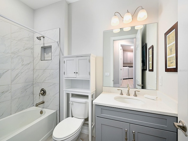 full bathroom featuring washer and clothes dryer, vanity, toilet, and tiled shower / bath