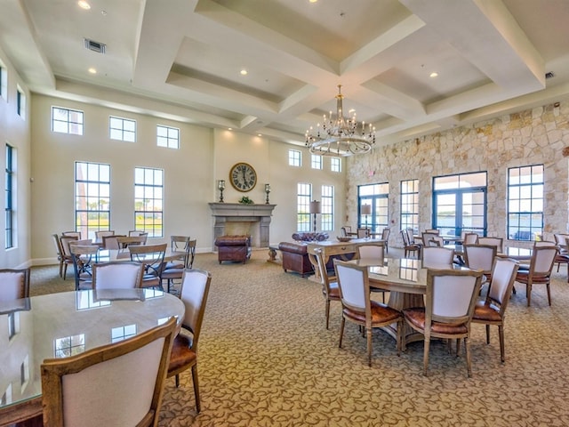 dining area with a towering ceiling, coffered ceiling, light colored carpet, a notable chandelier, and beamed ceiling