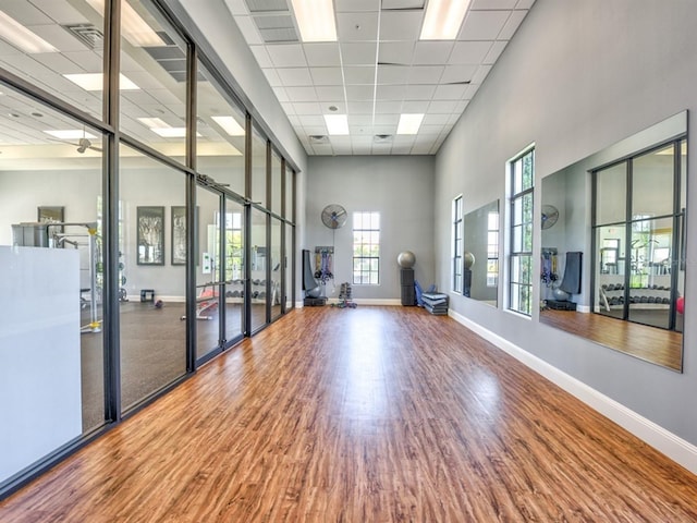 interior space featuring a paneled ceiling, french doors, a towering ceiling, and wood-type flooring