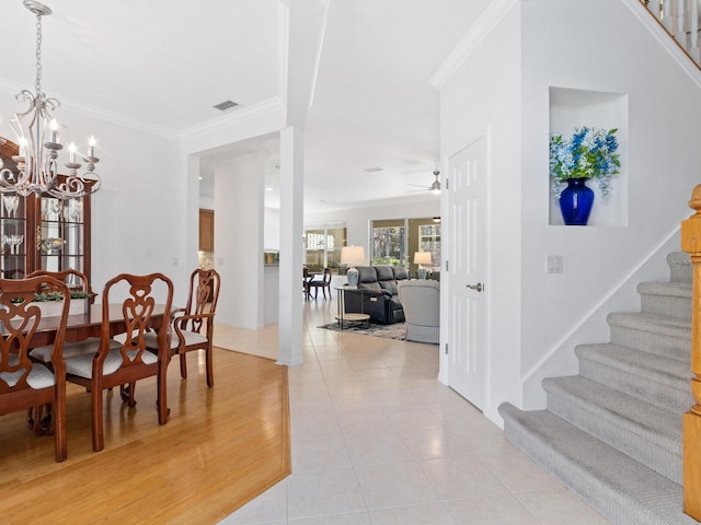 dining space with light tile patterned floors, ceiling fan with notable chandelier, and ornamental molding