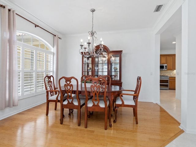 dining area with ornamental molding, light hardwood / wood-style flooring, and a notable chandelier