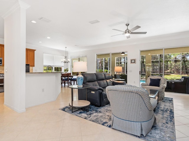 living room featuring ceiling fan with notable chandelier, a healthy amount of sunlight, light tile patterned floors, and crown molding